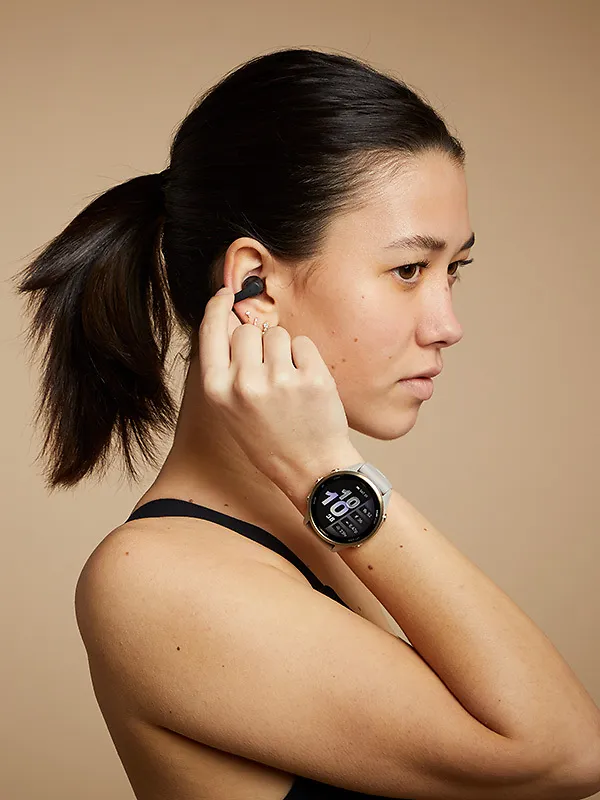 Woman wearing gps running watch putting in music ear buds
