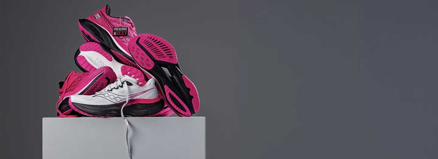 Pink and White Saucony shoes on a grey block styled for a photostudio photoshoot